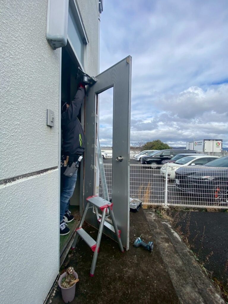 工場勝手口ドア改修工事中 新しいドア設置作業 岡山リフォーム