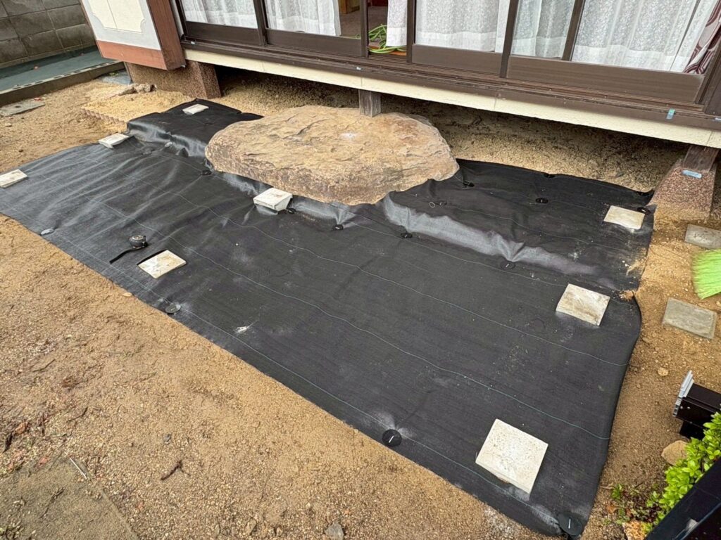 岡山県玉野市でウッドデッキ設置前に防草シートを施工している様子