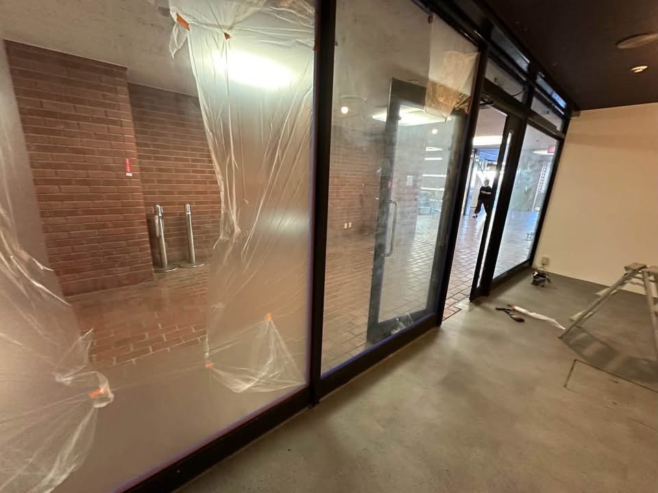 周囲をしっかり養生しながら進める店舗サッシの防錆塗料・下地塗装の様子